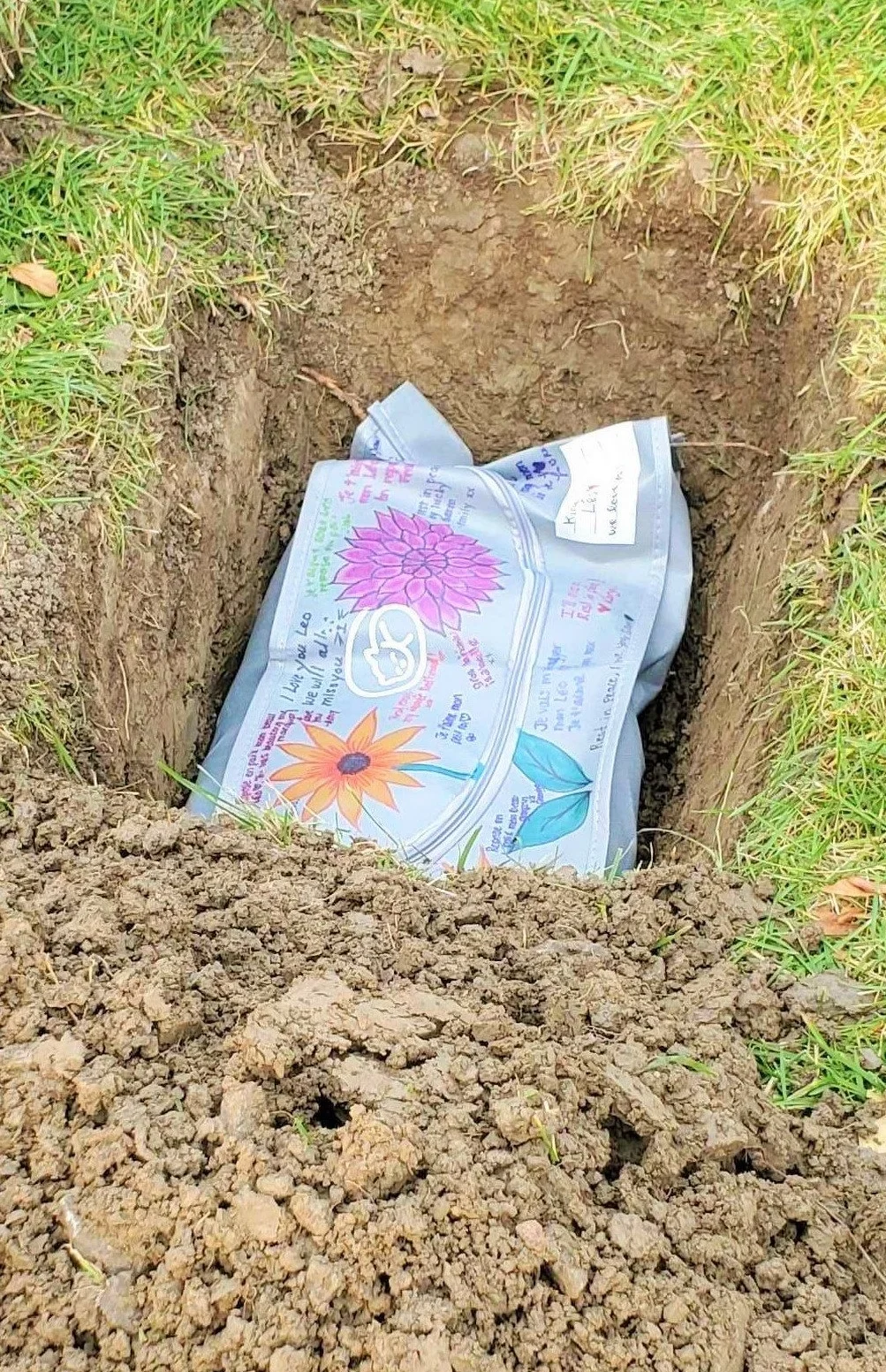 Image of a pet Euthabag in a grave. The bag has been decorated by the pet owners. The euthabag is used for burying your pet at home. 